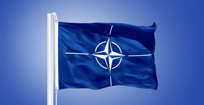 Natos flagga med en kompass på som vajar i luften.