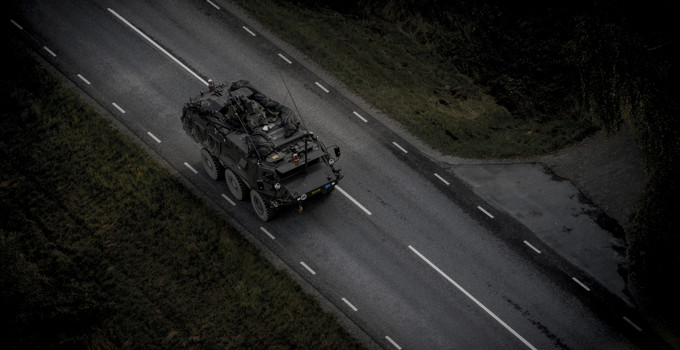 Ett militärfordon som kör längs en väg i mörkret.