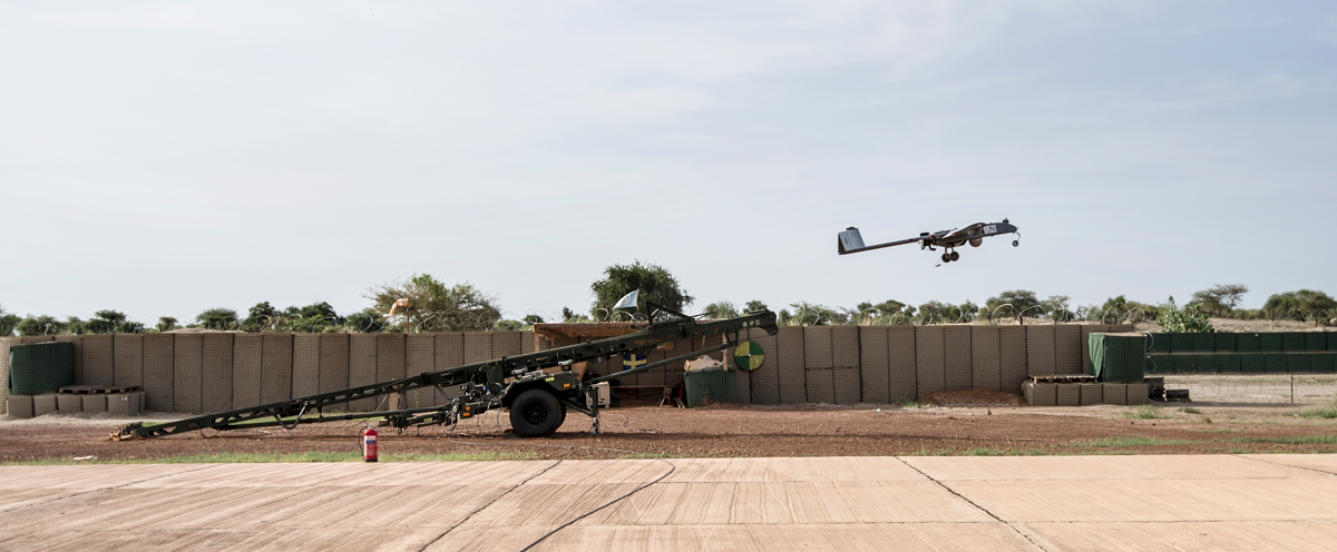 A drone is ejected over a dirt field..