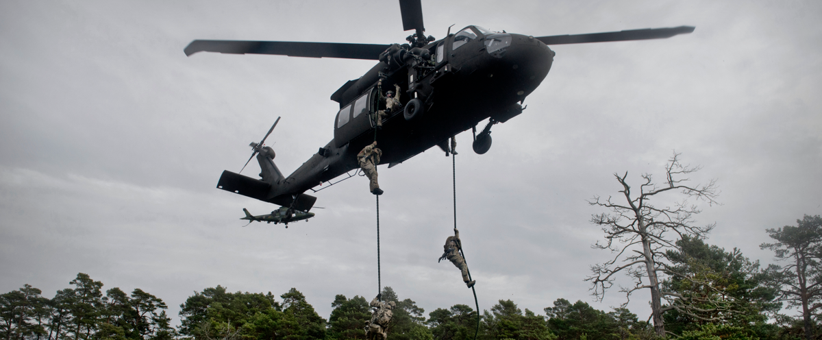 A helicopter is putting down soldiers to the ground.