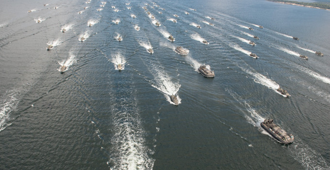 A large group of boats traveling across a large body of water.