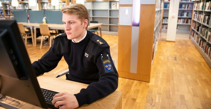 Kadett vid dator i biblioteket.