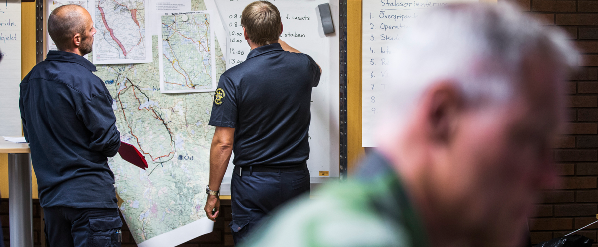 En grupp män som står bredvid varandra framför en karta.