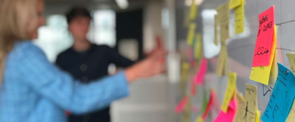 En man och en kvinna som tittar på post-it-lappar på en vägg.