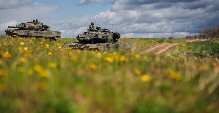 Militärfordon åker över en äng med maskrosor. 