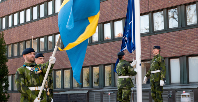 En grupp män som står bredvid varandra och håller i flaggor.