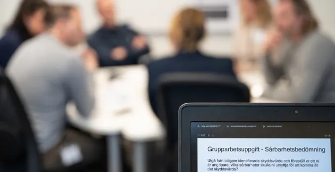 Blurrad bild av kursdeltagare med laptop i förgrunden.