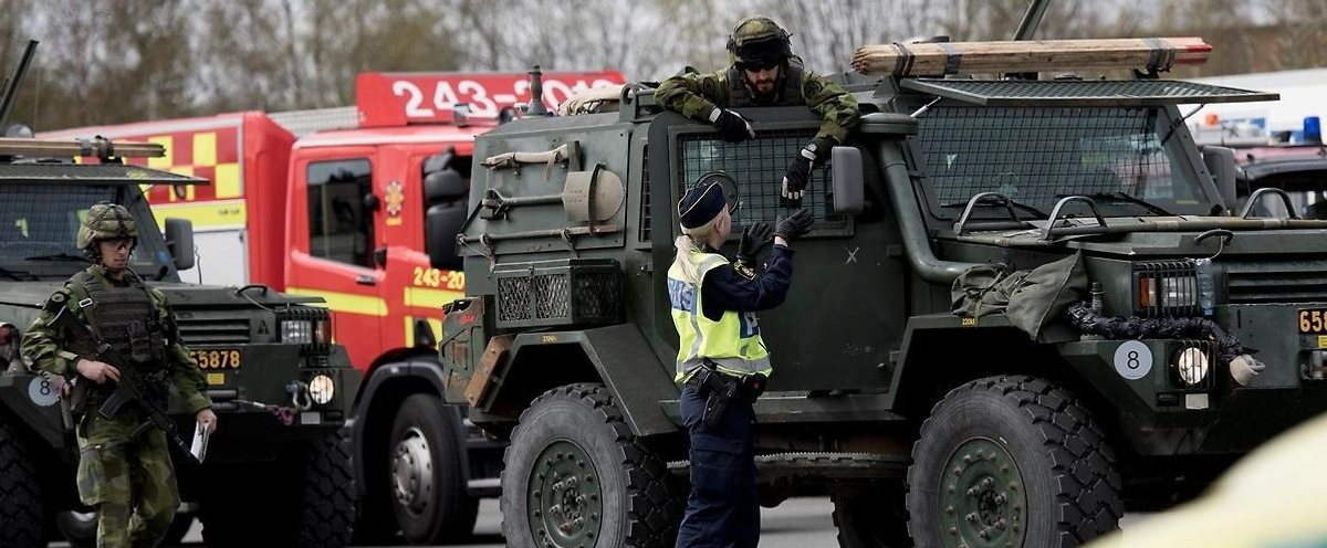 Personer som samtalar bredvid militärfordon.