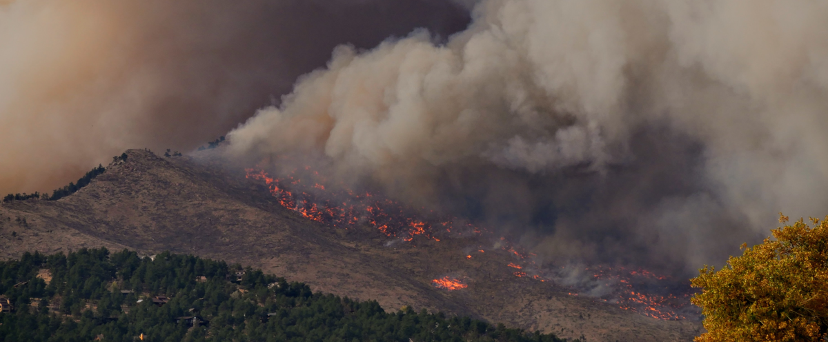 A large plume of smoke billowing from a mountain.