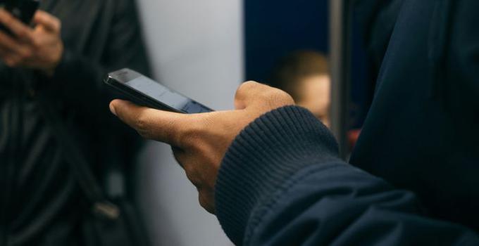 Hand som håller en mobiltelefon.