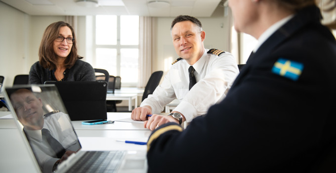 En kvinna och en man som sitter vid ett bord framför en bärbar dator.