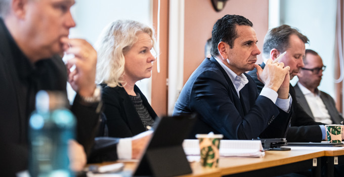 En grupp människor som sitter vid ett bord med bärbara datorer.