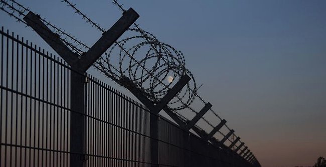 Barbed wire on top of a fence.
