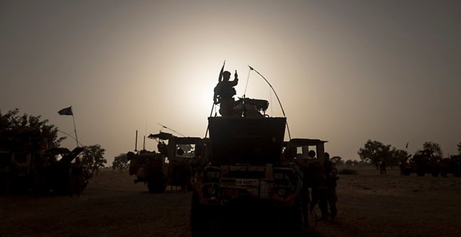 Militärt fordon och soldat i motljus