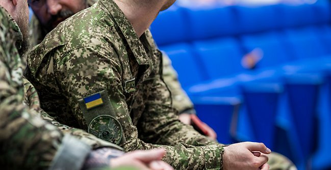 Man i ukrainsk uniform sitter i en föreläsningssal. 