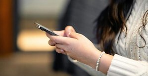 Närbild på kvinna som tittar på en mobiltelefon.
