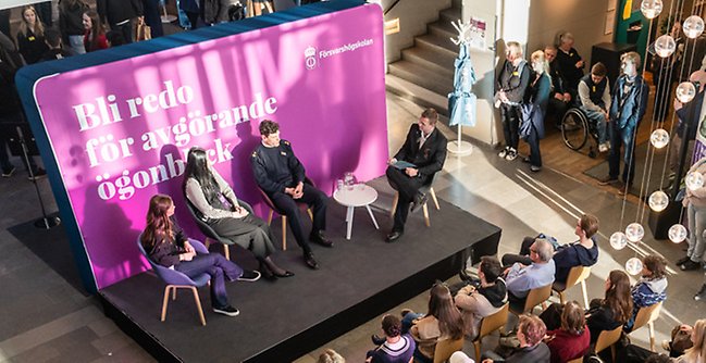 Forskare på scen framför publik.