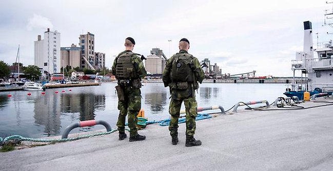 Två militärer med ryggen mot kameran på en kaj.